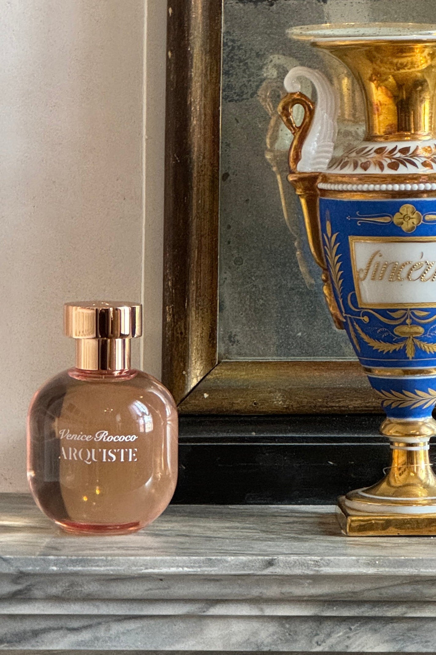 Arquiste Perfume bottle on a decorative shelf with a gold and blue urn in the background
