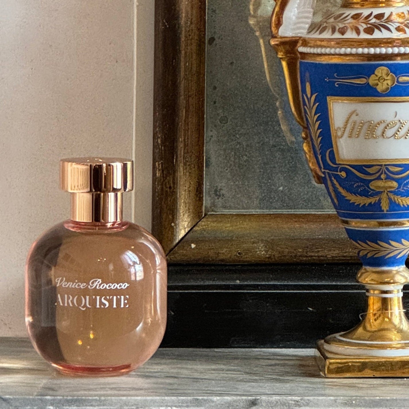 Arquiste Perfume bottle on a decorative shelf with a gold and blue urn in the background