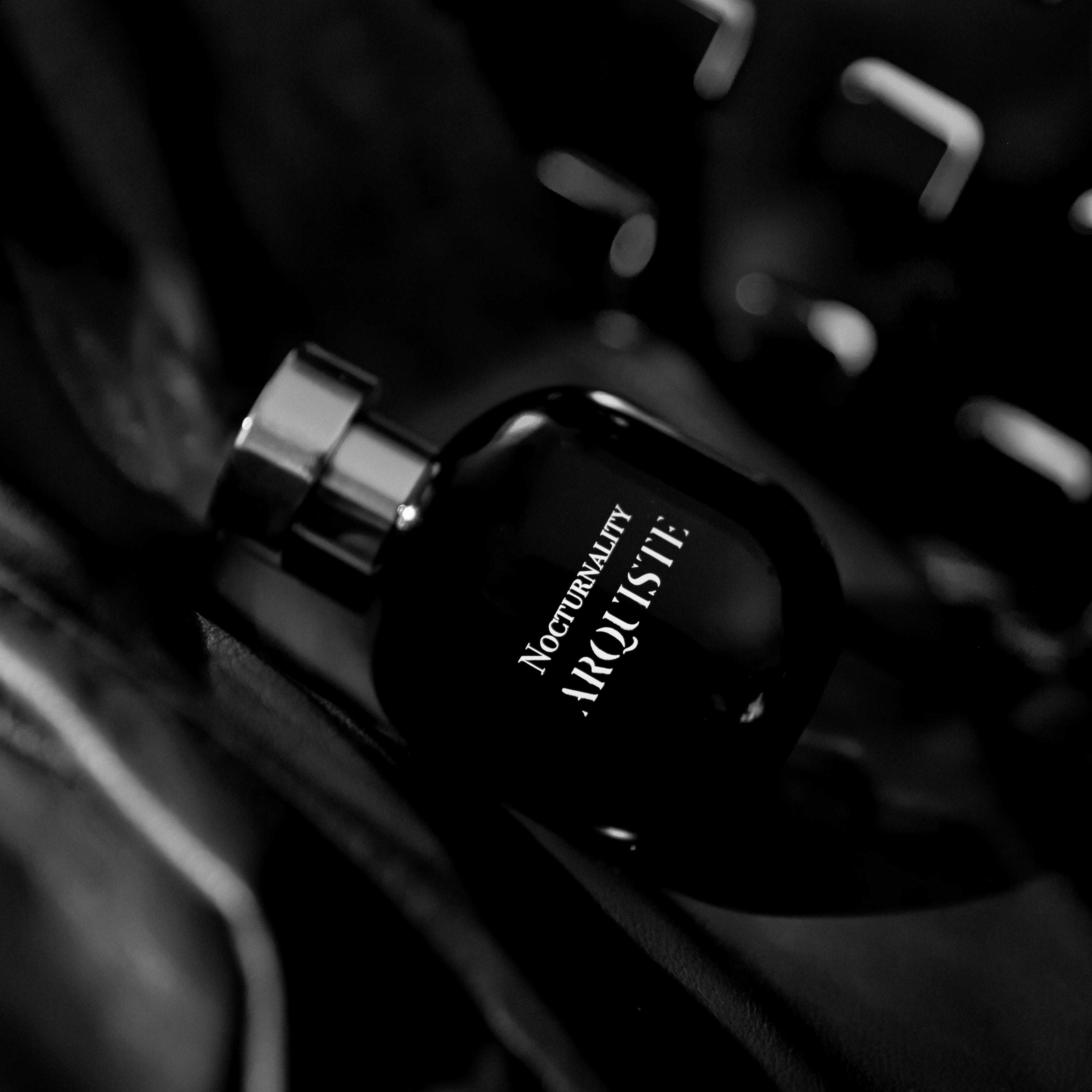 Black perfume bottle with 'Nocturnality' text on a dark background