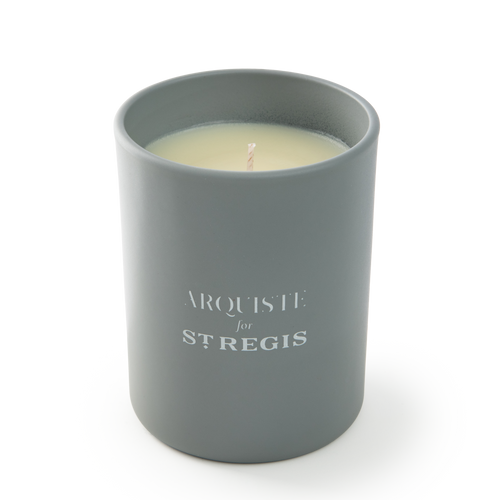Gray candle in a container with 'Arquiste for St. Regis' branding on a white background