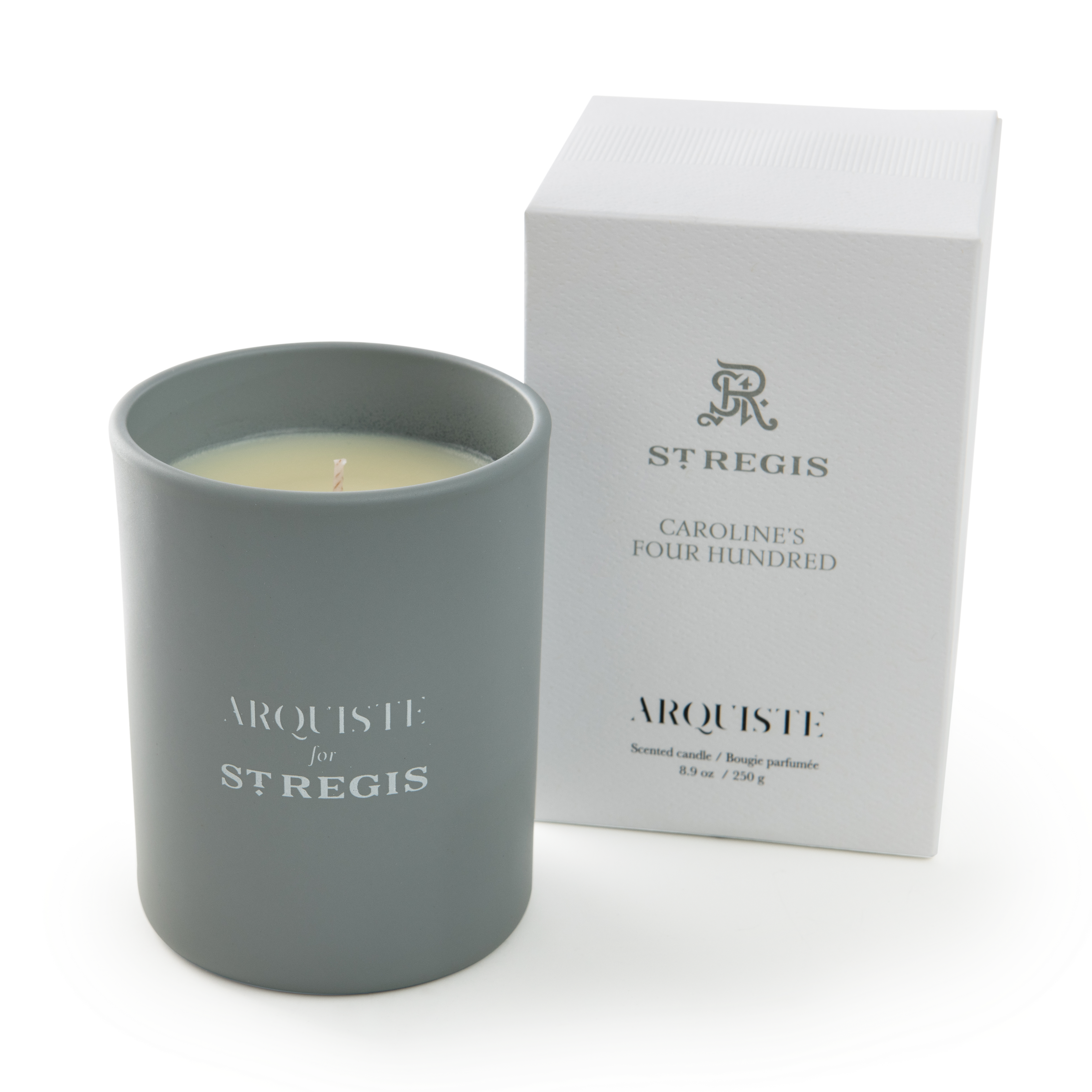 Gray candle with ' Arquiste for St. Regis' branding next to a white box on a white background