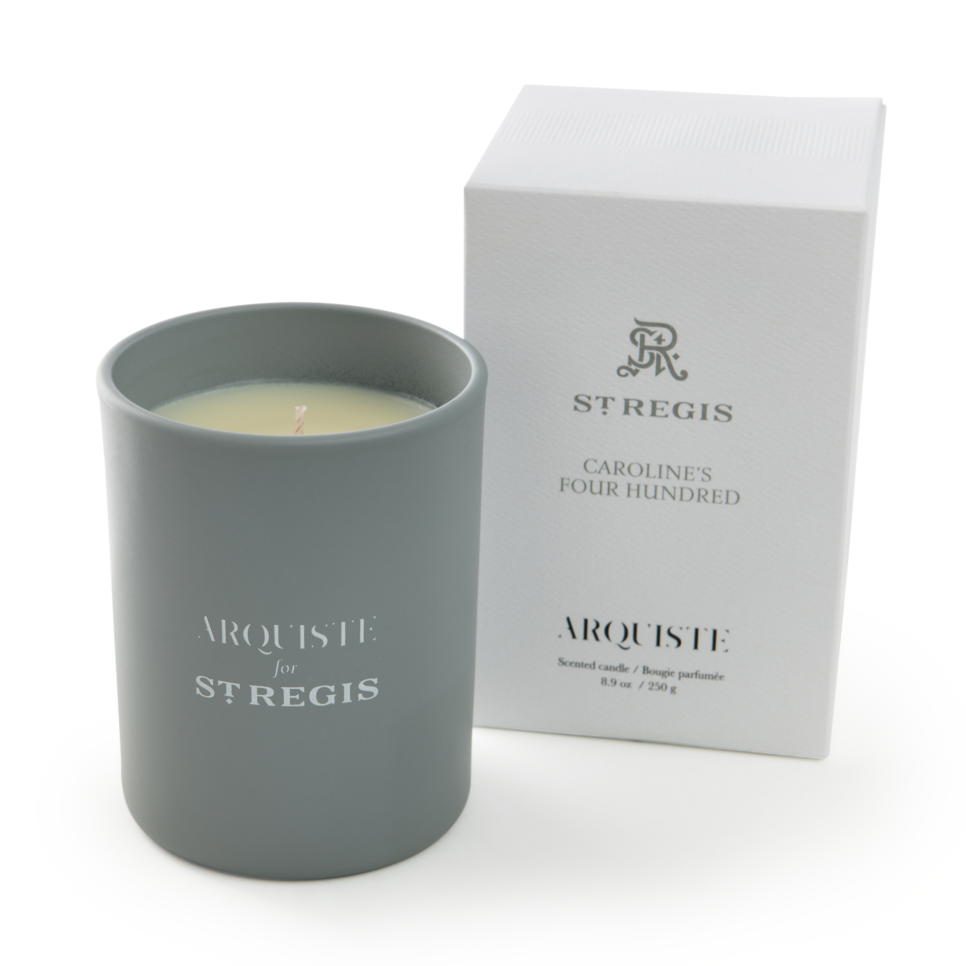 Gray candle with ' Arquiste for St. Regis' branding next to a white box on a white background