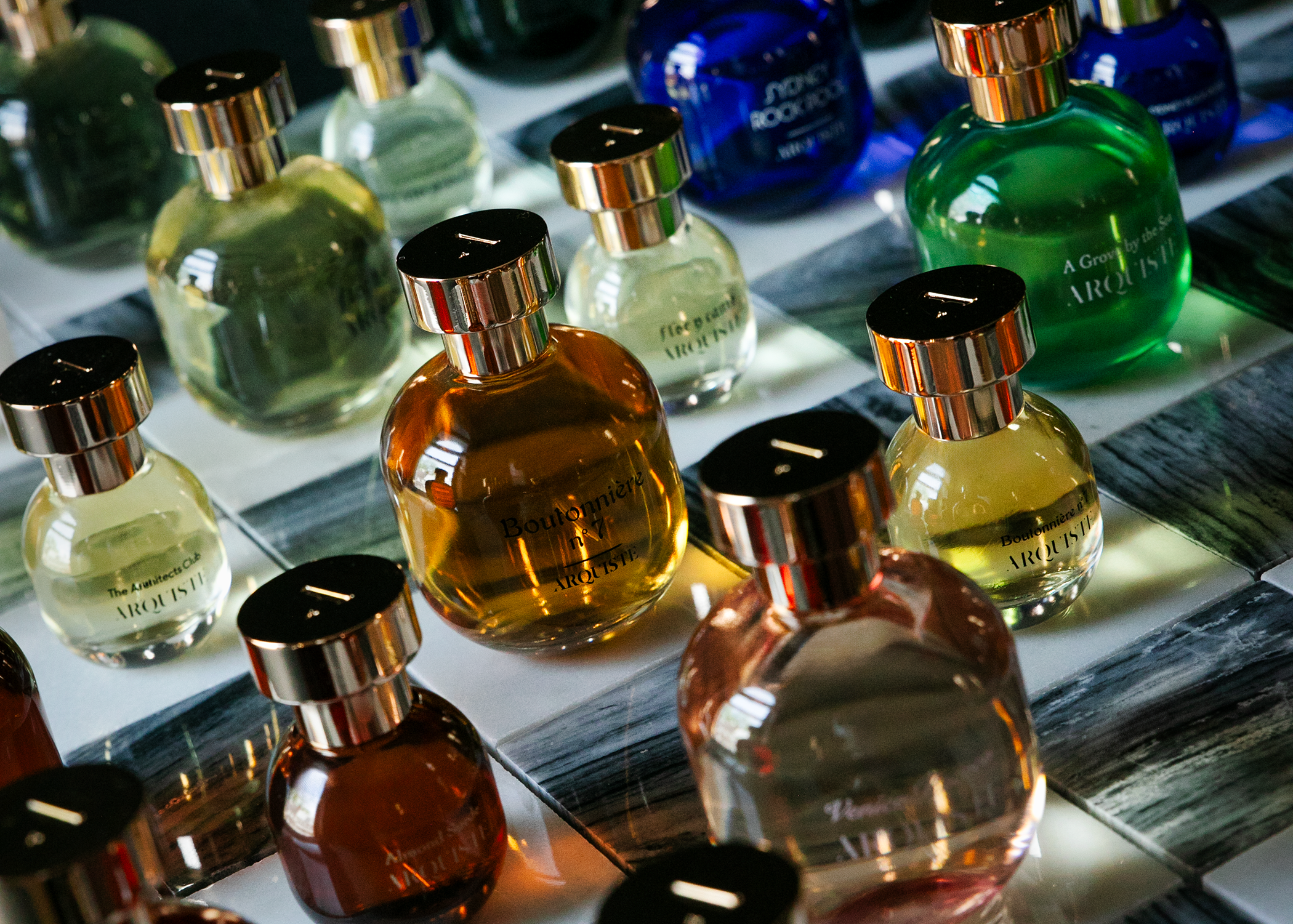 Collection of small perfume bottles on a reflective surface with a dark background