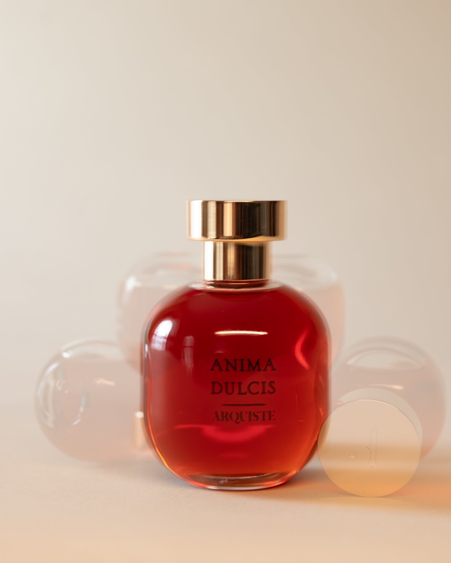 Perfume bottle with red liquid and gold cap on a light background